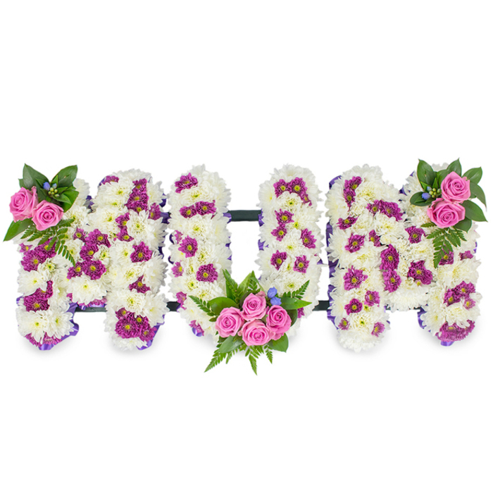 A lovingly crafted sympathy arrangement spells the letters MUM in substantial three-dimensional forms, each letter built from a dense carpet of immaculate white chrysanthemums that give a plush, tactile appearance. Scattered throughout the white base are measured accents of deep purple and magenta pom-poms which create subtle patterns and visual depth, while vibrant pink spray roses serve as intimate focal points: a small spray at the upper left of the first M, a more generous cluster set into the lower curve of the U, and a mirrored cluster on the upper right of the final M. Rich green foliage, including fern fronds, frames each rose cluster and lifts the composition with verdant contrast; tiny blue blossom highlights add a cool, delicate touch. The letters are gently outlined with a narrow purple ribbon, and a discreet dark horizontal bar connects them, giving the piece structural unity without detracting from the soft floral surfaces. The lighting is even and muted, chosen to emphasise texture and the floral craftsmanship rather than dramatic shadows, producing a calm, consoling impression. As a Canonbury florist might place it for a service at a nearby chapel or for a wake close to Essex Road, the tribute balances traditional symbolism - white for remembrance, pink for affection - with contemporary design accents. Crafted with measured care by Canonbury Flowers, it reads as both a public declaration of love and a private act of remembrance, conveying dignity, warmth and the quiet skill of a local flower studio.