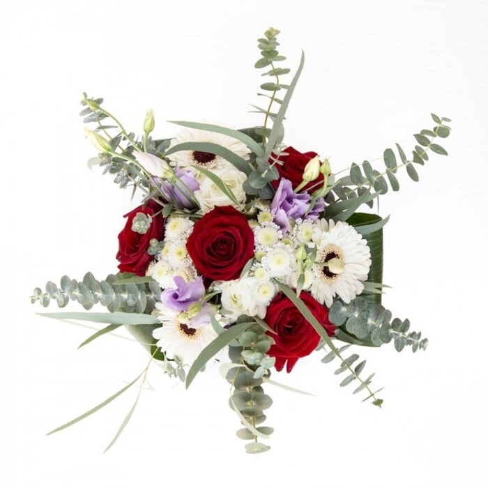 As an experienced Canonbury florist, I would describe this bouquet as a celebration of nuanced harmony-each stem chosen for its beauty and intent, each element contributing to an overall sense of refined confidence. The creamy, radiant petals of the white gerberas unfurl around espresso-dark centres, anchoring the composition with quiet strength. Spiralling red roses provide a lush counterpoint, timeless in their symbolism of affection and care, while slender stems of lilac lisianthus introduce a modern, pastel softness, their forms reminiscent of blooms caught in a gentle Canonbury breeze at dusk. Wisps of eucalyptus weave through the arrangement, their silvery-green discs catching the light and adding a subtle sense of movement, much like the shifting shade beneath Highbury Fields' trees. Fluffy white filler flowers gather in delicate tufts, softening the assemble with a cloudlike texture and hinting at the curated luxury of local flower markets near Upper Street. Strong, glossy leaves wrap the base, framing the palette and adding a sculpted, designer edge. Set in a clear vase, with stems submerged in clear water, the bouquet is a visual invitation to linger, to breathe in hints of rose and eucalyptus, to run fingers along the tactile foliage. Crafted for anniversaries, thoughtful gifts, or simply to adorn a contemporary Canonbury home, this arrangement reflects both tradition and the artistry that defines our neighbourhood's floral scene.