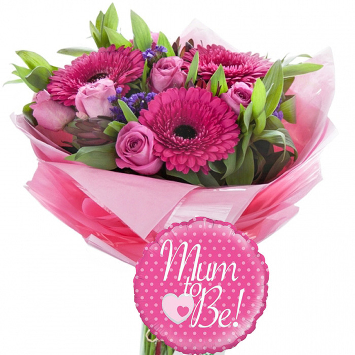 This image presents a radiant baby shower bouquet, thoughtfully styled as if ready for same-day delivery across Canonbury and the surrounding Islington streets. Positioned against a pure white background, the arrangement appears bright and fresh, with its colours crisp and clearly defined. Dominant within the bouquet are several fuchsia pink gerbera daisies, their smooth petals stretching outward like rays around deep, dark centres that add a sophisticated touch and anchor the design visually. Between these eye-catching blooms, pastel pink roses are carefully placed; some are still compact buds with just the edges tinged in deeper pink, while others are partially open, revealing soft, layered petals that curl gently at the tips, giving the bouquet a romantic, velvety texture. Threaded among the gerberas and roses are delicate clumps of tiny purple filler flowers, such as statice, which bring a soft haze of lavender tone and introduce a fine, airy detail that lightens the overall look. The arrangement is framed with an abundance of greenery, using both slim, arching leaves and broader, shiny foliage to create a rounded, classic hand-tied shape that feels complete and well-balanced. Around the stems, layers of pink tissue paper are wrapped with care, moving from light blush to stronger pink tones, forming a voluminous, ruffled collar that evokes femininity and celebration. Over the tissue sits a layer of clear, gently crinkled cellophane, reflecting light and enhancing the sense of a special, ready-to-give gift, much like one you might collect from Canonbury Flowers on your way to a baby shower off Essex Road. At the base of the bouquet, a small round foil balloon in vivid pink stands out, edged with a scalloped border and dotted playfully with white spots. Across the balloon, in graceful white script, the words Mum to Be! are written, with a charming heart motif-pale pink with a central white heart-placed just beneath the message. The overall scene communicates warmth, optimism, and joyful expectation, ideal for celebrating a pregnancy, welcoming a new chapter, or delighting an expectant mother at home or in hospital.