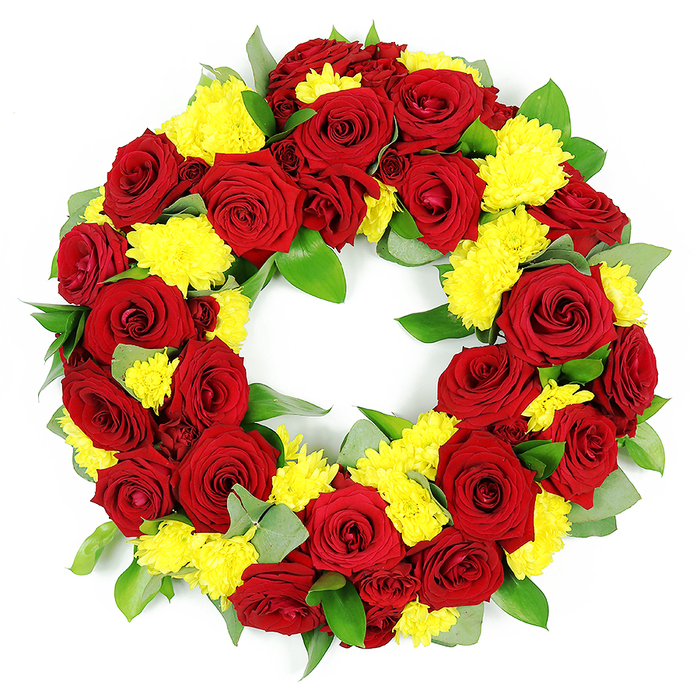A lush, circular funeral wreath filled with deep red roses and golden yellow chrysanthemums is presented against a brilliant white background, the clean setting making every petal and leaf stand out clearly. The wreath is composed as a true, even ring with a hollow centre, carefully built so that there are no obvious gaps, just a continuous band of flowers and foliage. The red roses, likely premium long-stem varieties cut short for the design, are fully open and placed close together, their velvety petals overlapping like layers of soft fabric. Each rose shows subtle variations in tone, from rich, classic red to slightly darker, wine-red outer petals, giving the arrangement a sense of depth and movement rather than a flat block of colour. In between the roses, clusters of small yellow chrysanthemums are packed tightly, their rounded forms and dense, feathery petals bringing a delicate, almost cushion-like quality to the design. A framework of greenery - probably a combination of glossy, dark salal leaves and cooler, blue-green eucalyptus - surrounds and interlaces these blooms. Some leaves curl gently at the edges, others lay flat, catching the light with a quiet sheen that suggests freshness and recent preparation, the way a local Canonbury florist might complete a tribute early in the morning before delivering to a service near Canonbury Square or along New North Road. Strong, even illumination enhances the vibrant reds and radiating yellows, while small shadows in the folds of petals create a sense of realism and tactility, as if you could reach out and feel the soft textures. The wreath communicates both solemnity and warmth, a suitable floral expression of remembrance, respect, and gratitude for a life well lived.