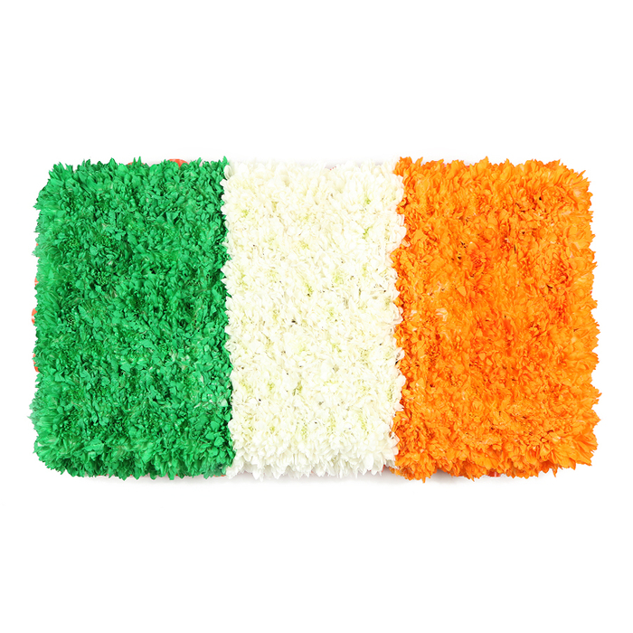 A vibrant, rectangular floral banner recreates the Irish flag with three equal vertical stripes-green on the left, white in the center, orange on the right-every inch formed from thousands of tiny petals. Against a pure white backdrop, the surface is richly textured, the green section resembling a soft, mossy carpet of blossoms, its uneven, organic plane revealing the close-knit clusters of petals. The central white stripe appears as a rounded, cloud-like band, its petals packed tightly to achieve a luminous, almost velvety texture that softly divides the colours while symbolising enduring peace. The orange stripe glows with a warm, candlelit glow, its petals stacked to mirror the other bands' density and depth, giving the flag a cohesive, handcrafted rhythm. The whole piece measures like a formal banner, precise in proportion and embodying a respectful, celebratory mood. The atmosphere carries the scent of fresh-cut blooms and the quiet pride of a local craft, ideal for stories about Ireland's heritage, St Patrick's Day celebrations, or national remembrance. Conceptually rooted in Canonbury's community-near Canonbury Road, Essex Road, and Upper Street-it speaks to neighbourhood pride and the artistry of Canonbury Flowers, offering dependable delivery across Canonbury and surrounding Islington areas.