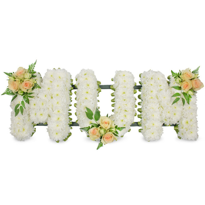 A refined and heartfelt floral display in the image spells MUM in large, uppercase letters, designed as a funeral tribute and photographed against a simple white background for clarity. The entire surface of each letter is covered in closely set white spray chrysanthemums, their tiny petals forming a soft, almost feathery texture that feels both delicate and strong. These chrysanthemum blooms sit side by side with no visible gaps, creating a solid, snowy base that speaks of purity, respect, and calm. Peeking subtly around the edges, a dark green frame and touches of foliage lightly trace the outline of each character, lending shape and support while also introducing a gentle contrast between the rich greens and the crisp whites. At three points along the word, small rose arrangements bring warmth and a hint of colour: one at the top left arm of the first M, one at the foot of the U, and a final one at the top right arm of the second M. These accents combine soft peach and blush pink roses in various stages of opening, from tight buds to fuller blooms, interwoven with fresh greenery and fern-like fronds that add natural movement and subtle fragrance. The overall impression is of a carefully considered tribute, the kind of piece you might see travelling from a family home near Canonbury Square to a local chapel of rest. It carries the quiet dignity of a final gift from children or grandchildren, expressing love, remembrance, and gratitude. Crafted by a skilled local florist familiar with Canonbury families and their traditions, this MUM floral tribute is ideal for placing alongside the coffin or at the front of the service, offering a tender, visually soothing focus during a time of loss.