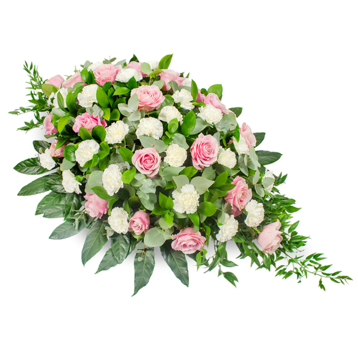 A large, teardrop-style sympathy spray is carefully presented against a stark white background, its elongated shape widening at the top left and narrowing down to a gentle point on the lower right, like a single falling tear captured in flowers. The arrangement is densely layered with soft pink roses at different stages of opening, from tight buds with just a hint of colour to fully unfurled blooms revealing intricate, velvety petals. Their blush-to-rose shades introduce warmth and tenderness. Interlaced between the roses are generous clusters of white carnations and spray carnations, their frilled petals adding lightness and texture, as though small cushions of cloud have been tucked among the blooms. Beneath and around this pastel canopy, rich greenery provides structure: broad, dark green leaves create a strong, polished base, while rounded eucalyptus in a silvery-green hue adds contrast and a quiet, herbal freshness reminiscent of walking through the leafy corners of Canonbury Square. Fine strands of deep green ruscus trail from the narrower end, enhancing the sense of gentle movement and lending the spray a natural, slightly cascading feel. The lighting on the image is soft and even, ensuring that every petal, vein, and leaf edge can be clearly seen without distraction. This traditional funeral arrangement, similar to those often requested for services in Canonbury churches or crematoria nearby, is designed to rest on a casket or be placed as a main tribute. It speaks of serenity, respect, and enduring affection, offering a comforting floral presence during moments of farewell and remembrance.