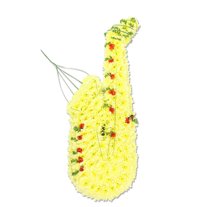 A large floral sculpture in the unmistakable shape of a saxophone is displayed upright against a bright, plain white backdrop, allowing the intricate craftsmanship to be fully appreciated. The body of the saxophone is completely covered with a dense blanket of sunny yellow chrysanthemum florets, each bloom carefully positioned so that no gaps of greenery show through, creating a continuous, buttery-yellow surface. This floral skin traces the entire form of the instrument: the sweeping neck that bends gently forward, the long central body, and the wide, open bell at the base that seems ready to project sound. Interspersed among the chrysanthemums are numerous tiny, deep red rosebuds and spray roses, thoughtfully placed to mark out the positions of the keys and key guards, giving the impression of a real instrument translated into flowers. Fine strands of dark green foliage and delicate trailing vine are threaded through sections of the design, especially along the outer contours and inner curves, adding definition and a sense of natural movement. Close inspection reveals slim metallic wires and structural stems emerging subtly near the mouthpiece and along the side, evidence of the careful engineering needed to maintain this three-dimensional tribute. The overall mood is tender and celebratory, something a Canonbury family might choose to honour a jazz musician, band member, or devoted music fan whose life bridged rehearsals, gigs, and evenings spent listening to records at home. The bright yellow suggests friendship, optimism, and the light they brought to others, while the red roses introduce a quieter note of devotion and respect, turning this floral saxophone into a deeply personal farewell at a funeral or memorial gathering.