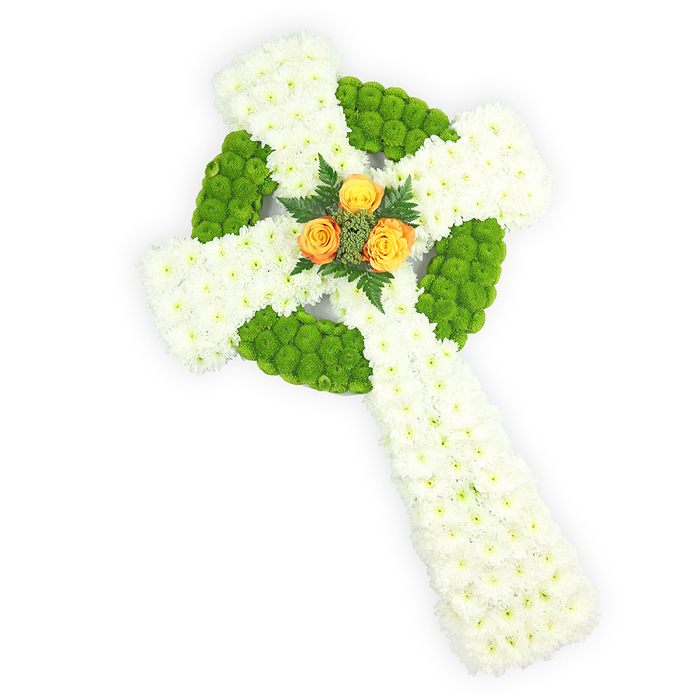 This image presents an elongated Celtic cross crafted entirely from fresh blooms, set against a stark white field and pictured from slightly above so the three-dimensional form reads clearly. The principal material is a dense field of small white spray chrysanthemums, packed to create a soft, almost cushion-like surface that signifies peace and purity. Bright, apple-green button chrysanthemums are woven through the white in purposeful bands: they outline the circular ring at the crossroads of the arms and occupy alternating sections along the horizontal span, their rounded textures carving rhythm and structure into the design and echoing traditional Celtic interlace. Anchoring the piece at its centre is a compact cluster of three vivid orange-amber roses; their warm, sunlit petals provide a striking emotional counterpoint to the cool whites and greens and are delicately set among deep green fern fronds that give a natural margin and subtle scent. The tonal trio of white, green and orange-yellow quietly evokes Irish colours and makes this arrangement particularly resonant for funerals or memorials celebrating Celtic heritage. The clear, soft lighting picks out petal edges and the layered relief of the cross, lending the composition gravitas and clarity. Florists in Canonbury frequently craft this style for services near Canonbury Square, local crematoria, or family homes along New River Walk, choosing it for its comforting symbolism and for the careful, respectful craftsmanship it communicates to grieving families.