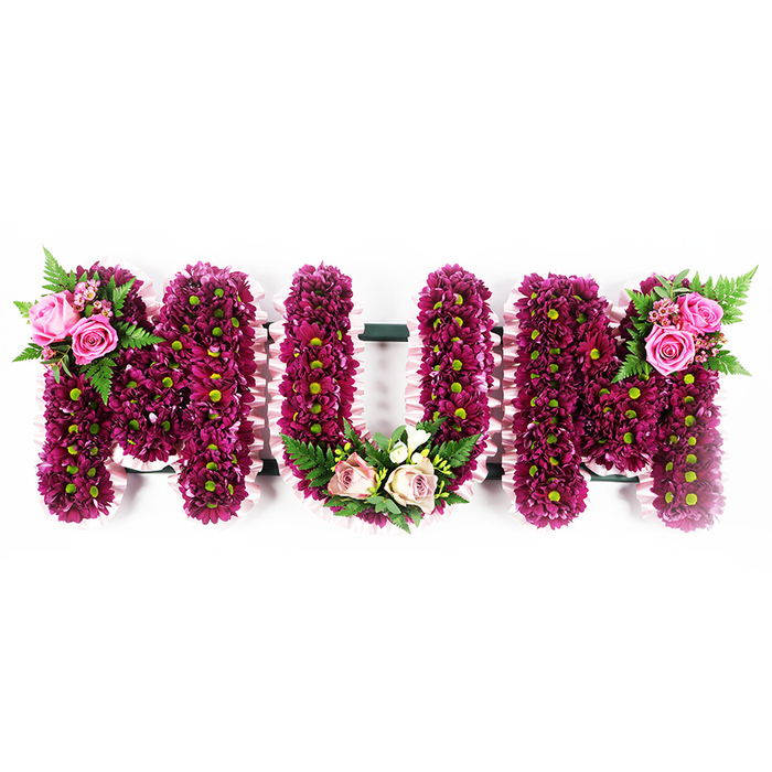 A large floral tribute spelling the word MUM stands out clearly against a crisp, white background, its bold lettering softened by layers of delicate petals. Each of the three letters is carefully formed as a solid, three-dimensional frame, then completely covered with masses of vibrant magenta and deep purple spray chrysanthemums. The blooms are packed tightly together, almost overlapping, so that the flowers create a rich, textured blanket with tiny lime-green eyes glimmering throughout. The outline of every letter is edged with a pale pink, ruffled ribbon, which runs smoothly along the sides and adds a gentle, almost vintage charm to the piece. The first M carries a focal arrangement on its upper left curve: open pink roses in full bloom, surrounded by smaller buds, glossy leaves, and light, airy fern fronds that bring height and movement. The U features its main accent at the base, where a soft mix of blush pink roses, creamy flowers, and variegated foliage forms a tender cluster that nestles into the curve, like a small garden gathered in the hollow of the letter. On the upper right of the final M, another grouping of bright pink roses and fresh greenery mirrors the first, bringing symmetry and a sense of completion. Crafted in the style often requested by Canonbury families for funerals or wakes near local churches and Islington chapels, this tribute speaks quietly of love, gratitude, and remembrance. It feels like a heartfelt final message to a mother whose presence shaped home and family life across the Canonbury streets.