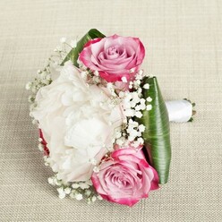 A lush, compact bouquet evokes the refined spirit of Canonbury, combining artistry and romance in every petal. You see two prominent pink roses, one anchoring the top-left, the other balancing the bottom-right, their petals radiating from deep magenta edges to a soulful blush and faint lavender at their hearts. Between them is a generously bloomed white peony, its many-layered petals forming a cushiony, cloud-like centrepiece that glows softly against the bouquet's backdrop. Sprigs of fresh baby's breath, with their myriad tiny white blossoms, float between the larger flowers, adding dimension and a gentle, ethereal texture. The bouquet's base is encircled by broad, glossy green leaves arranged in architectural folds, as if echoing the leafy avenues of Canonbury itself. The stems are bundled and smoothly wrapped in a pristine white satin ribbon, its tail suggesting readiness for a joyful aisle walk or a momentous celebration. Set against a woven beige fabric reminiscent of the artisanal textiles in local boutiques, the bouquet radiates an air of gentle anticipation and skilled craftsmanship. The even light glances over every detail, celebrating the subtle interplay of colours and textures. Perfect as a bridesmaid's bouquet or a classic wedding accent in Canonbury, this arrangement channels the area's timeless charm and natural serenity, promising freshness and beauty for any special day.