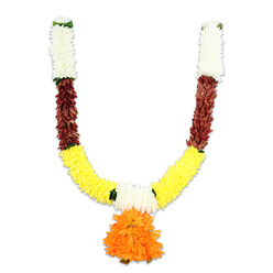 Soft morning studio light bathes a traditional U-shaped ceremonial garland, transforming ordinary materials into an emblem of welcome and celebration. From each hanging point the garland rises in a compact column of creamy-white florets, their rounded, cushiony forms recalling small chrysanthemums dusted with soft light. Directly below these pale crests, a band of rich reddish-brown provides contrast-textured, almost leathery in appearance, the elements read like layered petals or preserved foliage that lend a sense of age and rootedness. The arms then sweep down and inward into a generous field of golden-yellow, where tightly clustered, marigold-like pom-poms create a luminous curve that seems to radiate gentle cheer. Tiny green accents thread the transitions, like small leaves caught between blooms, offering a crisp counterpoint to the warm palette. Suspended at the centre is a lush, orange pendant - a dense, ruffled orb of petals that drops like a sunburst and commands attention as the garland's heart. The craftsmanship is evident in the uniform spacing and tactile fullness; the artificial fibres are stitched and bundled to mimic real blooms while offering longevity and ease of care. Visually, the piece sits on a clean white field, the colours heightened by studio illumination; emotionally, it reads as both festive and reverent. A familiar sight during festivals from Diwali evenings to Ganesh Chaturthi processions, this toran-style mala would sit naturally above doorways in Canonbury, near Canonbury Square or along Essex Road, signalling hospitality and auspiciousness for weddings, puja, or seasonal celebrations.