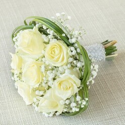 Radiating gentle sophistication and subtle romance, this Canonbury-inspired bouquet gracefully combines classic white roses with drifts of delicate baby's breath, conjuring the serene gardens found along Alwyne Road. Each rose boasts a creamy, almost buttery warmth as it reflects the ambient daylight, symbolizing new beginnings and heartfelt moments. Wisps of lacy gypsophila encircle each bloom, creating an effect akin to whisper-light snowfall resting upon velvety petals. Dynamic ribbons of fresh, looping bear grass add a touch of modern finesse, providing both structure and whimsy. The stems are gathered with precision, bound in a luminous silver-hued ribbon, then adorned with neat rows of luminous white pearls that invite gentle touch and elevate the design's tactile allure. Freshly cut ends extend slightly below, enhancing the organic beauty of the creation. Whether cradled by a bride or gifted in celebration of an anniversary near Canonbury Square, this thoughtfully crafted bouquet, available for delivery across N1, quietly enhances every meaningful occasion with its poised, tender radiance.