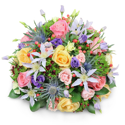 This image shows a beautifully rounded bouquet placed against a pure white background, the kind of clean setting that lets you imagine it resting on a polished table in a Canonbury townhouse. The flowers are densely gathered into a dome, every stem placed with intention so that no space feels empty and no bloom is hidden. Soft pink, warm yellow, and creamy peach garden roses form the core of the design, their layered petals curling gently like silk, some fully opened, others just beginning to loosen. Between them, delicate clematis flowers stretch out their star-shaped petals in shades of white and pale lavender, each bloom with a sunny yellow centre that draws the eye. Blue eryngium, or sea holly, introduces a striking, spiky counterpoint: their metallic blue-grey heads feel both wild and refined, echoing the textured charm of local gardens around Canonbury Square. Deep purple lisianthus blossoms weave through the arrangement, from tight, ruffled buds to softly opening flowers, lending depth of colour and a subtle sense of movement. Clusters of bright red hypericum berries gleam among the petals, adding a jewel-like brightness and a pleasing change in texture. The whole bouquet is cradled by lush foliage, including broad glossy leaves, feathery greens, and hints of darker, burgundy-tinged stems that tuck into the shadows. Light glances off the petals and berries, suggesting freshness and careful conditioning, as though the bouquet has just been prepared for same-day delivery to a home off Essex Road or a small gathering near New River Walk. The result is a harmonious, joyful arrangement that feels suitable for birthdays, anniversaries, or any moment when you want to send an uplifting, garden-inspired gift.