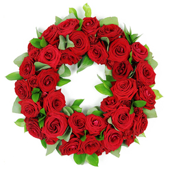 This circular wreath of crimson roses radiates solemn grace, set against a crisp white background that makes every bloom glow with quiet intensity. Each rose shows subtle shade variation, from tight vases of bud to fully opened petals, their velvety textures catching soft light and creating depth in the ring. Interspersed among the reds are fresh green sprigs-broad eucalyptus-like leaves with a matte finish and slender, glossy ruscus-that provide a natural, verdant contrast and a sense of field-grown abundance. The arrangement feels lush and three-dimensional, with petals and leaves gently overlapping to form a continuous circle that embodies continuity and tribute. In the Canonbury area, this classic floral circle would be a dignified choice for funerals, memorials, or anniversaries, quietly conveying love, respect, and consolation. Its presence suggests a moment of reflection, a shared memory brought to life through colour and texture. For those seeking thoughtful remembrance in Islington, the wreath offers both beauty and meaning, ready for delivery to families nearby, with freshness maintained from stem to bloom and a scent that lingers softly in the air.