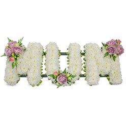 Delicately constructed to spell the word "MUM" in upright capital letters, this sympathy piece is entirely covered with tiny, crisp-white chrysanthemums or similar spray blooms, each flower placed close to its neighbour to form a seamless, plush surface. The white palette reads as calm and reverent, while three modest clusters of muted colour give the arrangement its intimate highlights: a grouping of soft lavender roses and a single pale pink bud on the upper left arm of the first M, a similar pairing tucked into the U's central dip, and a final pastel cluster set on the upper right arm of the last M. These roses - varying from tight bud to softly unfurled petals - bring a faint, honeyed rose scent and a tactile contrast to the cushiony chrysanthemums. Luminous green foliage, including narrow fern fronds and fresh leaf sprays, weaves through the letters and frames the pastel accents, adding movement and definition. A dark green support structure, possibly wrapped in ribbon or moss, is visible as a shadowed outline along the base, ensuring the letters remain perfectly formed for standing display. Bathed in soft, even light, the tribute communicates comfort and respectful remembrance; it is intended for use at a funeral service, memorial, or graveside. As a local Canonbury florist might arrange for families around Essex Road, Upper Street, or Canonbury Square, this piece can be prepared and arranged with care for delivery to nearby chapels and churches.