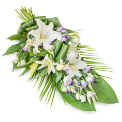 A refined sympathy spray in cool whites and greens stretches diagonally across a stark white background, its form reminiscent of a single, flowing brushstroke of remembrance. Central to the piece are several white oriental lilies, some in full, dramatic bloom, others still partly closed, their smooth petals curving outward as if in a quiet gesture of farewell. Their centres show gentle, yellow-green stamens, adding subtle contrast without disturbing the overall calm. Nestled among these larger blooms are clusters of lisianthus, their delicate, bell-like flowers mostly white but tinged at the petal edges with soft lavender, like the last light along the paths of nearby Highbury Fields. Numerous tight buds, both of lily and lisianthus, give the design texture and a sense of depth, as though memories are layered one upon another. A generous collar of foliage anchors the composition: broad, glossy dark leaves form a strong base, while slender palm-style fronds fan outward on the right, enhancing the elegant, tapered shape. A few leaves are artistically rolled and shaped by an experienced Canonbury florist's hand, giving the tribute a modern, sculptural note while still feeling timeless and respectful. The spray appears cool and fresh, with the imagined fragrance of lilies gently present but never overpowering, like a quiet presence at a wake or funeral service in one of Canonbury's intimate chapels. This floral composition feels designed for those moments when words fall short, offering instead a graceful, living gesture of condolence and love.
