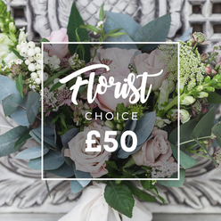 This lush, hand-tied bouquet evokes a late-spring cutting garden arranged for timeless elegance. At its center sit soft blush roses, their layered petals like satin, surrounded by bright white berries and delicate sprays of small white flowers that lend an airy, textured veil. Dusty blue-green eucalyptus fans through the composition, its rounded leaves carrying an unmistakable, calming scent that balances the sweetness of the roses. Small, deeper pink and burgundy accents tuck into the shadows to give the arrangement depth, while a few taller green-and-white flower spikes break the silhouette and add gentle movement. The stems are bound with a cream-coloured ribbon, visible at the base, speaking to careful hand-tying and thoughtful finishing. The bouquet is photographed against an ornate, pale carved stone or plaster backdrop-softly out of focus-to emphasise the flowers' natural colours and the refined, slightly rustic styling. Soft ambient light bathes the arrangement, creating a soothing, uplifting atmosphere suitable for quiet celebrations: sympathy, a milestone birthday, or a comforting thank-you. A neat white rectangular label overlays the image with script lettering reading 'Florist' above 'CHOICE' and a displayed price '?50', signposting a florist-curated option. As a local florist's piece, this bouquet feels rooted in Canonbury's relaxed, cultivated neighbourhood charm-imagining delivery to Canonbury Square, along St Paul's Road or over to Newington Green-bringing fresh seasonal blooms that smell of eucalyptus and morning dew and arrive ready to make a delicate, considered impression.