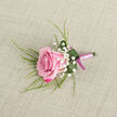 On a pale beige, linen-like cloth that recalls the calm, neutral tones of a well-loved Canonbury townhouse, a handcrafted boutonniere is laid out with care, inviting the eye to linger over each thoughtful detail. At its centre is a single pink rose, angled slightly across the lower left of the frame, its velvety petals layered in a graceful spiral. The colour deepens to rich fuchsia along the petal edges, then softens into a baby pink glow toward the tightly curled heart, suggesting a bloom freshly chosen from a local market off Upper Street. Clusters of crisp white Baby's Breath nestle around the rose, their tiny, cloud-like flowers creating a soft halo of lightness and contrast. Slender, grass-like strands of greenery emerge from behind, arching gently outward like brushstrokes, adding movement and natural rhythm to the composition. Embracing the base of the rose is a single, glossy emerald leaf, curled into a smooth collar. A few bright droplets of water cling to its surface, catching the light and hinting at cool morning mist over nearby Canonbury Gardens. The stems are neatly wrapped in a satin ribbon of pale pink, the fabric smooth and slightly lustrous, wound with the careful precision of an experienced florist. At the very end, a darker magenta-pink ribbon is tied into a small, tidy bow, echoing the rose's deeper tones and adding a discreet flourish. The overall effect is one of poised, romantic simplicity, perfectly suited for a groom or prom guest in Canonbury, a refined accent for weddings, civil ceremonies, or intimate celebrations across Islington.