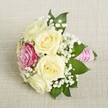 Nestled on a pale, softly-woven fabric, a compact wedding bouquet lights up the calm ambience of Canonbury with its sophisticated blend of colour and detail. Five creamy white roses, their petals gently unfurling and luminous, form the bouquet's foundation, offering a sense of tranquil beauty reminiscent of local garden squares. In their midst, a single vibrant magenta rose gleams slightly off-center-a splash of bold cheerfulness that captures the celebratory mood of North London festivities. Fragile tufts of gypsophila (baby's breath) diffuse among the blooms, lending an airy and lighthearted grace, while deep green leaves at the base evoke the lush foliage found along Canonbury's tree-lined avenues. The stems are expertly gathered and bound in a bright pink satin ribbon, spiraled with tiny white pearls that glimmer softly and add a final note of timeless sophistication. The bouquet, softly illuminated, feels alive with hope and gentle joy-evoking images of bridal parties gathering on mild spring mornings, or elegant events along Upper Street. Each detail speaks to the loving touch and creativity of Canonbury's local florists, making this arrangement an exquisite companion for weddings, anniversaries, or any moment where elegance and heartfelt celebration meet in the heart of Islington.