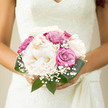 This image shows a beautifully composed wedding bouquet, photographed close-up so that every petal and texture can be appreciated. At the centre are generous creamy peonies, their petals densely layered and softly ruffled, like ivory silk gathered into delicate rosettes. They carry the impression of gentle movement, as though they are still unfolding in the morning light over Canonbury Square. Surrounding the peonies, roses in shades of dusty pink and soft lavender nestle closely together, each bloom in a slightly different stage of opening. Some are still cupped and modest, while others reveal their spiralled hearts, lending a sense of time and anticipation to the design. Wisps of white gypsophila weave through the arrangement, dotting the bouquet with tiny, cloud-like blossoms that create space and air between the larger flowers. Around the outer edge, rich green foliage provides structure and contrast, its darker tones making the pastel colours appear even more luminous. The bouquet has a hand-tied, compact silhouette, clearly shaped for a comfortable bridal grip as she moves between Canonbury's quiet streets and nearby Islington venues. The lighting is natural and gentle, with no harsh shadows, enhancing the feeling of calm, understated luxury. It suggests a wedding day that is intimate and thoughtful, where every detail-including this bouquet-is meant to echo harmony, love, and a sense of grounded beauty rooted in the local surroundings.