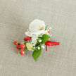 A close-up, top-down photograph of an elegant white orchid boutonniere resting on a softly textured, oatmeal-coloured linen fabric, the kind of natural backdrop you might see on a Canonbury townhouse table laid ready for a wedding morning. At the heart of the floral piece is a single pristine Phalaenopsis orchid bloom, its broad, velvety petals opening like porcelain wings around a gentle throat brushed with creamy yellow and soft orange, suggesting warmth and quiet joy. Nestled around the orchid, tiny cloud-like tufts of white baby's breath create a halo of delicate texture, their miniature blossoms forming a light, airy mist that plays beautifully against the smooth orchid petals. Deep, glossy green leaves of varying shapes and sizes peek out from beneath the flowers, offering a fresh, garden-like contrast that recalls the leafy calm of nearby Highbury Fields. To one side, a compact cluster of round, shiny red berries adds a vivid, festive pop of colour, while paler green buds hint at new growth and seasonal abundance. The stems are gathered neatly at the base and wrapped in a rich red satin ribbon, tied in a tidy knot with short, elegant tails that suggest the piece is ready to be pinned to a lapel for a wedding, winter prom, or Christmas celebration in and around Canonbury. The gentle daylight, natural fibres, and refined colour palette together convey a sense of craftsmanship, intimacy, and thoughtful preparation, as if a local florist has just finished the final details before delivering it to a groom, best man, or special guest.
