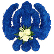 A bold, ceremonial Sikh Khanda floral tribute dominates the scene, its form outlined with precision against a bright white background that accentuates every curve and blade of the emblem. The entire symbol - the upright central sword, the encircling chakkar, and two outward-sweeping kirpans - is carpeted with tightly massed royal blue chrysanthemums or similar clustered flowers, placed so close that they form a seamless, velvety blue surface. The shade is a deep, regal blue, calm yet commanding, echoing the quiet dignity of remembrance services held in and around Canonbury. At the centre base of the vertical sword, a small posy of white and green flowers forms a gentle focal point. Three immaculate white roses rest there, each bloom fully shaped with layered petals that appear soft to the touch. They are surrounded by delicate sprays of tiny white flowers, likely gypsophila, and framed by small arcs of rich, dark green foliage, adding a natural contrast and a sense of freshness. The arrangement is lit in a way that creates subtle, soft-edged shadows beneath the design, giving the Khanda a feeling of depth and substance, as though it could be lifted and carried to a Gurdwara or family home for a funeral, memorial, or anniversary of passing. Every element speaks to careful craftsmanship and an understanding of Sikh symbolism: the strong, protective blue, the pure white suggesting peace and prayer, and the considered balance of each floral detail. It is a moving tribute, designed to honour a cherished individual with quiet grace and devotion.