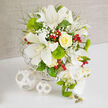 On a smooth white table, framed by a warm, textured beige backdrop that could belong to a quiet Canonbury terrace, a meticulously crafted bouquet becomes the focal point of the scene. Its palette is built on serene whites and layered greens, accented with just enough yellow and red to create a gentle, celebratory mood. Several white Oriental lilies dominate the center, their open petals sculptural and luminous, revealing speckled throats and prominent stamens that draw the eye inward. Nestled nearby, a single yellow rose curls in a perfect spiral, its creamy petals tightly packed yet plush, suggesting both tenderness and strength. Fine sprays of white baby's breath drift between the bigger flowers like soft mist, while vivid, round tufts of Green Trick dianthus add a tactile, mossy texture that invites the imagination to touch. Feathery greenery fans out around the design, giving it an organic, garden-grown character, as if freshly gathered from a hidden corner of Highbury Fields. Glossy red hypericum berries punctuate the arrangement with jewel-like pops of color, hinting at festive gatherings and joyful toasts. Flowing down the right side, a cascade of white Phalaenopsis orchids introduces movement and grace, their petals satin-smooth and their centers dusted with subtle yellow and green. The blooms are anchored in a discreet white woven basket, echoed by two white wicker spheres placed artistically to the left on the table, reinforcing the sense of careful design. This image captures the essence of modern wedding flowers and elegant event décor, the kind Canonbury residents might choose for an intimate ceremony, anniversary dinner, or refined celebration at home.