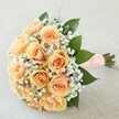Radiating gentle elegance, this Canonbury-inspired bouquet is perfectly suited for cherished milestones and weddings across the local community. Dozens of peach and apricot roses are nestled tightly together, each blossom a study in warmth, with petals that spiral out in rich, creamy gradients-from a soft blush at the edges to deeper apricot at the center-capturing that timeless romance known in Canonbury's leafy avenues. Wispy white gypsophila encircles the roses, as delicate as vintage lace, offering an airy lightness that frames their beauty without competing for attention. Sprigs of deep green leaves peek beneath, providing freshness and a sense of renewal reminiscent of local green spaces. The bouquet's hand-tied stems are wrapped securely in a peach satin ribbon, its surface dotted with pearls that add classic romantic texture and a silky, cool feel. Set against a softly woven, pale linen background and bathed in gentle daylight, every detail gleams with a mood of hope, joy, and quiet anticipation-an arrangement crafted for unforgettable Canonbury celebrations, available for heartfelt same-day deliveries throughout the neighborhood.