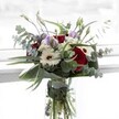 Inspired by the tranquil charm of Canonbury's garden squares, this bouquet artfully balances boldness with delicacy. Deep crimson roses mingle with pristine white gerberas whose dark chocolate centres convey subtle glamour and warmth. Graceful arcs of eucalyptus branch outward, their silvery-green leaves catching ambient light in much the same way as dawn breaks over the Regent's Canal. Pale lilac lisianthus, both open and budded, nestle between the larger blooms, offering a soothing, pastel contrast that feels contemporary and uplifting. Lush, shiny foliage hugs the bouquet's perimeter, giving the whole arrangement a sense of lush abundance, while petite white filler flowers cluster like cloudbursts within. The bouquet sits proudly in a clear glass vase, where every fresh green stem can be admired-a testament to the expert curation of Canonbury's local florists. There's a gentle mingling of eucalyptus and rose in the air, evoking both renewal and memory. Composed for moments of gratitude, comforting gestures, or as an inviting centrepiece for an Islington family table, this bouquet is a thoughtful expression of beauty and sincere sentiment, with every detail reflecting the artistry and warmth of the community it was crafted to serve.
