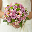 A romantic wedding bouquet is shown in soft, natural light, its colours echoing the gentle, artistic character of Canonbury's tree-lined streets. At its centre, a cluster of lilac and lavender roses forms a serene focal point, their petals layered and velvety, opening in tight spirals that suggest trust and continuity. Surrounding the roses, sprays of pink alstroemeria stretch outward, their slightly speckled petals and pale yellow throats giving the impression of butterfly wings poised for flight. They add a sense of openness, as though welcoming guests to a ceremony in a local townhouse or an elegant reception near Canonbury Square.
Bright green button chrysanthemums are tucked between the pastel blooms, their round shape and zesty chartreuse colour bringing a lively contrast that keeps the design from feeling overly sweet. Interlaced among them, airy clouds of white gypsophila scatter like tiny stars, softening the transitions between blooms and creating depth, so the eye moves gently across the arrangement rather than landing in one place. Glossy, deep green foliage cradles the bouquet, framing the flowers and giving structure without heaviness, while the stems are bound neatly together in a compact, hand-held shape.
The way the light falls across the petals enhances their fresh, almost dew-kissed appearance, as if the bouquet has just been collected from a nearby morning market. The mood is quietly joyful and deeply personal-perfect for a wedding, vow renewal, or special anniversary celebration in Canonbury. You can almost imagine the faint mingling fragrances of rose and greenery following the couple along cobbled paths, turning this bouquet into a living keepsake of the day.