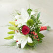 On a pale, woven linen-like surface, a luxurious hand-tied bouquet is presented at a gentle diagonal, as if just set down on a table in a Canonbury townhouse after being delivered from a nearby florist off Essex Road. The composition is led by striking white oriental lilies, several blooms fully open with trumpet-shaped petals that curl back gracefully, revealing faint reddish speckles and softly shaded throats. Around them, plump green buds promise more flowers to come, adding a sense of unfolding time. Cradled close to the lilies, a single, luscious red rose forms a dramatic focal point, its velvety petals layered in a precise spiral that suggests deep affection and timeless romance. Two round tufts of Green Trick dianthus sit like little green pom-poms, their fuzzy texture inviting the fingertips and offering a contemporary twist. Fine sprigs of baby's breath weave through the arrangement like a light, white mist, while clusters of small, shining red hypericum berries tuck in between petals and leaves, mirroring the rose's rich hue and lending a touch of winter warmth. A generous collar of greenery surrounds the flowers, from glossy, dark foliage to airy, grass-like strands that extend outward, creating flowing lines and a sense of movement, as though a breeze from nearby Canonbury Square has brushed across the bouquet. The stems are gathered neatly and wrapped in a wide band of red satin ribbon, its sheen catching the soft daylight and suggesting celebration, perhaps an anniversary dinner on Upper Street or a romantic proposal at New River Walk. Shadows fall gently across the neutral fabric, giving depth and dimension to an arrangement that feels both modern and timeless.