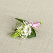 On a soft oatmeal-toned linen backdrop, this elegant boutonniere unfolds like a quiet love note, each element placed with calm assurance. The focal bloom is a creamy white alstroemeria-style flower, its open petals velvety and luminous, with refined reddish-brown speckles tracing the inner throat and adding depth, much like fine ink on handmade paper. Clustered around it are smaller white buds and half-open flowers that recall campanula or lily-of-the-valley, their smooth, porcelain-like surfaces catching the light in gentle highlights. Airy sprigs of white baby's breath weave between them, forming a delicate halo of tiny blossoms that softens the composition. To one side, a bright chartreuse-green cone of tightly packed buds, likely ornithogalum, introduces an unexpected vertical line and a contemporary texture, echoing the fresh greenery seen along Canonbury's garden squares and leafy terraces. Broad, dark green leaves cradle the arrangement, while wisps of fine, arching foliage curve outwards like brushstrokes, giving the piece a natural, almost wind-swept grace. At the base, a glossy pink satin ribbon wraps the stems, finished in a trim little bow that hints at celebration-perhaps a wedding ceremony at the local town hall or an intimate gathering in a Canonbury townhouse. The natural daylight in the image accentuates the boutonniere's freshness, suggesting cool petals, faint green fragrance, and the gentle rustle of leaves. It feels like a thoughtful, quietly refined floral accent, ideal for adorning a lapel, cuff, or small wrist corsage when marking a milestone or sharing affection across the neighbourhood.