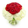 A sophisticated anniversary bouquet is presented in a simple studio-style setting, photographed against a bright white background so that every nuance of the flowers stands out. The arrangement forms a near-perfect sphere, with a tight cluster of deep red roses crowning a lush mound of white hydrangeas, all gathered into a clear, round glass vase. At the top, about ten to twelve red roses sit shoulder to shoulder, their velvety petals layered in rich spirals that create a sense of depth and dimension. The roses vary slightly in openness, some showing off the full complexity of their centres while others remain more modestly cupped, giving the impression of a living, breathing cluster rather than something overly rigid. Below, the white hydrangeas are packed densely together, each tiny floret contributing to an overall impression of softness and abundance, like a pillowy cushion supporting the passionate red blooms above. The creamy white tones of the hydrangea provide a serene backdrop that makes the crimson roses appear even more vivid and romantic. Through the transparent sides of the bowl-shaped vase, you can see the slender green stems gathered neatly in clear water, a reminder of the arrangement's freshness. The overall design feels calm, balanced, and deeply romantic-something a Canonbury couple might place in the centre of their table after a walk through nearby Highbury Fields, a simple yet meaningful way to celebrate years of shared memories and quiet, enduring affection.