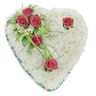 A quiet, tender heart formed entirely from a dense cushion of pristine white chrysanthemums rests against a clean white backdrop, its surface soft and textured like a cloud. The chrysanthemums are packed closely to create a seamless, muffled field of tiny petals that suggests purity and calm. From the upper left a sweep of deep crimson roses crosses the heart: three richly coloured blooms clustered together amid glossy ruscus leaves and delicate, fern-like fronds, with a few slender blades of bright green bear grass arcing outward to give subtle movement. Two other single red roses punctuate the composition - one near the upper right curve and another at the lower point - each surrounded by small green accents and tiny white filler blossoms that nod like whispered memories. A narrow emerald green satin ribbon borders the heart, tracing the shape with a refined, somber edge that frames the flowers without distraction. The lighting is soft and even, casting gentle shadows that accentuate the rounded forms of the chrysanthemums and the velvety depth of the roses; the roses' warm, powdery scent sits quietly above the cool, green fragrance of the foliage. The overall impression is one of composed dignity and intimate sympathy, a piece shaped by careful hands to offer solace. As a local florist in Canonbury we often place such heart tributes at services around Canonbury Square or deliver them to family homes near New River Walk, where the arrangement's classic whites and reds read as a calm, heartfelt farewell and a lasting visual expression of love and remembrance.