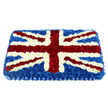 A large Union Jack floral tribute dominates the scene, crafted with the kind of precision that comes from many years of floristry experience. The rectangular design sits against a plain white backdrop, allowing the patriotic red, white, and blue colours to stand out clearly. A bed of deep blue chrysanthemums forms the main field of the flag, their compact heads pressed closely together to create a smooth, cushion-like surface that appears gently raised at the centre. Over this, clean white bands of tightly packed blooms shape the bold vertical and horizontal cross of St George, running from top to bottom and side to side with crisp, straight edges. Diagonal streams of velvety red carnations cross the design, forming St Patrick's Cross; they are edged with slim corridors of white flowers that sharpen every angle and preserve the accuracy of the Union Jack pattern. The fresh petals catch the light with a soft, natural sheen, and subtle shadows between the blossoms lend the tribute a sculpted, almost textile-like quality, as though a fabric flag has been reimagined in flowers. A pleated ribbon of royal blue trim lines the bottom of the arrangement, adding a polished finishing touch reminiscent of formal ceremonies or military honours. This is the kind of dignified piece Canonbury families might choose for a funeral or memorial service, perhaps for someone who lived near Essex Road or walked regularly through Highbury & Islington, and who held their British roots dear. More than decoration, the tribute conveys solidarity, gratitude, and a deep sense of national remembrance.