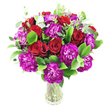 A lush, rounded bouquet of deep crimson roses and vivid magenta-purple carnations sits in a simple clear glass vase, the sort of arrangement a neighbour might carry home after a stroll past Canonbury Square on a sunny morning. The roses range from tightly furled buds to gently unfurling blooms, their velvety spirals catching the light and suggesting a warm, classic romance. Interspersed among them, the carnations offer frilly, ruffled layers in a rich, almost fuchsia purple that introduces a playful, modern contrast and a tactile, feather-like texture. Bright glossy greens - likely ruscus and similar foliage - swell the base of the bouquet, creating a full, emerald backdrop that makes the reds and purples sing, while slender, silvery eucalyptus sprigs lift the composition with airy shapes and a faint, refreshing eucalyptus scent that would breathe through a small flat on Upper Street. The transparent vase reveals clean stems and water, reinforcing a fresh, pared-back aesthetic against the white background that lets each colour pop. Light seems to graze the petal edges, giving the arrangement a soft inner glow and highlighting the florist's careful clustering into a dense, luxurious dome. This design reads as both celebratory and intimate - ideal for anniversaries, heartfelt congratulations, or to brighten a birthday table in a Canonbury home. A gentle, floral fragrance is implied rather than loud, the combination of rose sweetness and the green, resinous note of eucalyptus balancing the overall impression. The overall effect is expertly composed yet comfortably familiar, a bouquet that feels like a thoughtful, tactile gift from a local florist to someone you love.