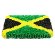 In this photograph, the Jamaican flag is rendered as an elegant, three-dimensional floral-style tribute, crafted as a solid rectangle that appears almost like a plush artwork rather than a simple flag. The piece rests against a bright white background, ensuring that the colours and textures stand out with striking clarity. A bold golden-yellow diagonal saltire dominates the centre, its X-shape formed from thousands of tiny, crumpled, flower-like elements that create a tactile, almost velvety ridge running from corner to corner. This vivid cross cleanly divides the panel into four triangular fields. The upper and lower triangles are filled with lush green textures, densely packed to evoke the feel of thick grass or a living moss wall, while the side triangles are constructed from rich black, velvety forms that give the design weight and a quiet, dignified presence. The edges of the tribute are visible, revealing its depth and suggesting that it has been carefully mounted as a funeral or memorial display, perhaps for a service in Canonbury or along the nearby streets towards Essex Road. Gentle, even lighting falls across the surface, highlighting the intricate folds and subtle shadows within each petal-like piece, and emphasizing the care and craftsmanship that went into its creation. The overall mood is one of respectful celebration of Jamaican heritage and heartfelt remembrance, a piece that speaks of love, identity, and community, well suited to honouring a life lived between Canonbury and the Caribbean.
