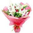 A richly detailed bouquet of white Oriental lilies and deep red roses is shown in close focus against a seamless white background, highlighting both its elegance and freshness. At the centre, large lilies open gracefully, their white petals forming wide, trumpet-shaped blooms that curl gently backward at the tips, while a few buds remain closed or just beginning to unfurl in pale shades of green and cream. In each open lily, dark orange-brown to cocoa-coloured anthers sit prominently, dusted with pollen, adding depth and a slightly rustic touch to the otherwise pristine white. Clusters of red rosebuds weave through the lilies, their petals tightly layered and velvety, suggesting romance and sincere affection. Around this pairing, a rich collar of foliage creates a sense of fullness and structure: broad, dark green leaves reflect a subtle gloss, while slender, grass-like fronds arc and twist, softening the silhouette. The entire arrangement is cradled in layers of bright pink, glossy cellophane or floral wrap, pulled up around the stems in billowing folds that catch and scatter the light, giving the bouquet a celebratory, gift-ready appearance. At the very base, a slim, lime green ribbon is tied neatly, its sharp, citrus tone standing out against the pink and green. The bouquet feels ideal for delivery to homes and offices throughout Canonbury-perhaps as a surprise for a birthday brunch off Essex Road, a thank-you gesture near Newington Green, or a Mother's Day treat sent from afar-offering a blend of pure white serenity and passionate red warmth in one thoughtfully composed design.