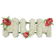 A dignified three-dimensional tribute that reads 'MOM', crafted to comfort and remember. Each bold letter stands out against a pristine white background, formed from hundreds of small, snow-white spray chrysanthemums packed so closely they create a soft, cloud-like surface with a subtle powdery scent. The dense blooms curve gently to give each letter a cushiony, tactile presence; from a short distance the letters read as pure white panels, while up close the individual blossom heads and tiny yellow centers become tender, intimate details. Three glossy red anthuriums-heart-shaped, waxy and tropical-are placed as focal accents: one on the upper left of the first 'M', another nestling at the base of the 'O', and the third crowning the upper right of the final 'M'. Each anthurium shows its pale yellow-white spadix and reflects soft daylight with a satin sheen. Around them, clusters of deep green foliage and feathery fern fronds provide a cool, textural counterpoint, while thin, arching blades of grass and stems trace gentle lines that link the red blooms across the letters, visually unifying the piece. A subtle dark green internal frame peeks at the edges, giving structure and shadow so the letters read clearly even from a distance. The overall mood is one of quiet, attentive reverence - a classic funeral tribute for a beloved mother that balances purity and warmth. The clean palette of white chrysanthemums and dramatic red anthuriums, composed with care and lit by soft natural light, speaks of love, remembrance and the calm dignity hoped for at wakes, services or graveside farewells.