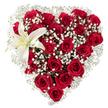 Set against a crisp white background, this heart-shaped floral tribute reads as a quiet, intimate declaration of love. Dozens of deep crimson roses are packed tightly to form the unmistakable heart silhouette; each rose reveals velvety petals in a range of blooming stages from tight, hopeful buds to wide, sensual blossoms, their dark red tones catching soft highlights and shadow to suggest depth and warmth. Tiny clusters of white baby's breath (Gypsophila) are woven thoughtfully between the roses, their star-like florets creating a cloud-like halo that lightens the composition and adds a breathy, ethereal texture between the heavier blooms. Nestled in the upper-left curve, a single large white lily opens like a quiet whisper - its broad, pristine petals edged with the faintest creamy yellow toward the throat, where yellow stamens punctuate the bloom and suggest a gentle, powdery scent. The contrast of textures - plush, velveteen rose petals, feathery gypsophila, and the lily's smooth, wax-like surface - encourages the eye to travel across the heart, discovering detail and care at every turn. The arrangement reads as both classic and refined, a floral language of devotion suited to anniversaries, Valentine's gestures, or an elegant sympathy tribute. As a local florist working near Canonbury Square and the New River Walk, I imagine this piece arriving softly to a doorstep in Canonbury or along Essex Road, its delicate perfume filling a room and the composition conveying sincere, handcrafted intent without the need for words.