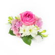 Against a pristine white background a compact, hand-crafted corsage reads like a pocket poem of spring: a lush bubblegum-fuchsia rose takes centre stage, its tightly furled inner petals softening outward into a plush blossom that seems to glow in cool daylight. Around this focal rose, clusters of pale pink and lavender hydrangea florets build a gentle, cloud-like volume, their papery edges offering a tactile contrast to the rose's velvet. Two creamy, trumpet-shaped blooms-small amaryllis or lily-like flowers with faint green throats-nestle just below, introducing an airy brightness and a whisper of garden-fresh scent. Deep, glossy green leaves fan from the base, broad and reassuring, while slender, vibrant green buds tipped with a hint of yellow rise like tiny promises of more colour to come. At the lower right a small cascade of luminous white pearls, varied in size, drifts delicately among the petals, adding a classic, heirloom touch evocative of bridal accessories. The composition sits in soft, natural light that makes each texture clear: the rose's plushness, hydrangea's delicate flutters, the lilies' satiny throat, and the cool sheen of the pearls. This piece reads as both a ceremonial accent and an intimate keepsake-ideal for weddings, proms, or an anniversary moment in Canonbury or nearby Islington, carried from a local market stall on Essex Road to a church near Canonbury Square. A florist's careful hand is evident in the balance of colour, scent, and scale, creating an arrangement that feels fresh-cut, elegant, and quietly celebratory.