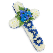 A large, elegant cross-shaped sympathy tribute rests on a bright white background, its outline clean and immediately recognisable. The cross is completely covered in compact white spray chrysanthemums, their rounded petals overlapping to create a dense, pillowy texture that suggests softness and serenity. Around the entire edge, a royal blue satin ribbon is carefully pinned and gently pleated, following every curve and angle and adding a deep, jewel-like border that contrasts beautifully with the snow-white blooms beneath. At the very centre of the cross, a striking cluster of blue flowers forms a focal point: lush, ruffled blue carnations paired with more slender, spiked florets reminiscent of blue delphiniums or orchids, all surrounded by rich, dark green leaves and airy fern fronds. The blue tones range from vivid cobalt to softer, ocean-like shades, echoing the tranquillity of nearby New River Walk on a quiet Canonbury afternoon. Down the length of the vertical bar, the tribute becomes personal, with the word DAD lovingly spelled out using loops and gathered segments of the same royal blue ribbon. Each letter stands proudly against the white chrysanthemum base, clearly marking this arrangement as a memorial for a father. The lighting is soft yet bright, ensuring every bloom, leaf, and ribbon fold is well defined, while a faint shadow beneath hints at its dimensional depth. This floral cross captures a mood of gentle dignity and remembrance, the kind of bespoke funeral arrangement families in Canonbury might choose to honour a much-loved dad at a church, crematorium, or graveside service.