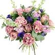 This hand-tied bouquet, shown clearly against a white background, feels like a moment of calm gathered from the streets around Canonbury into one generous armful of flowers. At its core, open garden roses in gentle blush, antique rose, and soft mauve unfold in layered spirals, their velvety petals creating a sense of intimacy and romance. Around them, frilled carnations add a playful texture, with each petal shifting from creamy, almost porcelain centres to edges kissed with blush and deeper pink, like watercolour washes that deepen towards the rim. Breaking through the softness, rich indigo and royal blue flowers - including a standout anemone with a dark, almost black heart and several more closed, tulip-like buds - lend a bold note of contrast, reminiscent of twilight skies over nearby Islington terraces. Slim stems of pale lavender and lilac stock weave lightly between the larger blooms, their many small florets adding both scent and a gentle, vertical lift. Embracing the entire arrangement, rounded, silvery eucalyptus leaves mingle with glossy dark green foliage, offering structure and a suggestion of clean, green fragrance. The gathered stems at the base reveal the bouquet's hand-tied nature, as if it has just been finished on the workbench of a Canonbury florist preparing same-day delivery to homes around Canonbury Square or along the quiet lanes leading to Newington Green. The overall impression is both soothing and refined, a bouquet that invites lingering appreciation and suits heartfelt occasions - from anniversaries and congratulations to a simple, thoughtful gesture of care.