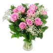 A fresh, carefully composed bouquet of pink roses and baby's breath rests in a clear glass vase, photographed against a bright white background that allows every soft colour and texture to emerge with clarity. The design centres on roughly a dozen pink roses, their petals opening in concentric swirls from deeper rosy cores to lighter, blush-toned outer edges. Some blooms are wide and open, while others are still in the early stages of blooming, creating a gentle sense of growth and anticipation that harmonises beautifully with baby celebrations. Nestled among the roses, airy stems of white baby's breath form delicate clouds of tiny blossoms, giving the arrangement a light, almost weightless feel-as if a little puff of Canonbury morning mist had been gathered and tucked between the petals. Dark green rose leaves frame the flowers, adding both structure and a rich contrast that makes the pink and white tones appear even more luminous. Through the clear glass of the vase, the green stems are clearly visible, neatly trimmed and standing in clean, fresh water that reflects the studio lighting. That lighting is soft and evenly spread, enhancing the velvety texture of the petals and the fine, lacy detail of the Gypsophila without overpowering the scene. The overall impression is calm, tender, and joyfully understated, ideal for baby flower deliveries to homes around Canonbury, Essex Road, and nearby family-friendly streets. It is easy to imagine this arrangement placed beside a cot or on a living room mantel, offering a subtle, fragrant reminder of love, welcome, and the quiet wonder of new life.