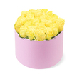 A luxurious cluster of yellow roses fills a round pastel pink hatbox so generously that the flowers appear to spill softly over the rim, forming a full, domed canopy of petals set against a crisp white background. The roses are arranged with almost architectural precision, their velvety petals spiralling tightly from deep, buttery centres to lighter, lemon-tinted edges, giving the bouquet a sense of depth and movement. Tiny hints of green foliage peek out here and there, barely visible among the densely packed blooms, just enough to remind you of the stems and leaves supporting this glowing crown of flowers. The hatbox itself is a smooth, cylindrical container in a gentle blush pink, with a matte finish that recalls velvet or brushed suede, lending a tactile richness that complements the softness of the roses. Even, diffused lighting washes over the composition, heightening the contrast between the bright yellow flowers and the pale pink box while leaving the background pure and unobtrusive. The mood is one of cheerful elegance, like a carefully chosen surprise arriving at a Canonbury doorstep near Highbury & Islington, ready to be placed straight onto a dining table or bedroom dresser. It feels perfect for marking birthdays, anniversaries, or simply sending a burst of happiness to a friend across North London. In this image, the timeless charm of yellow roses is given a contemporary twist, echoing the calm, creative spirit of Canonbury's tree-lined streets and thoughtful, design-led interiors.