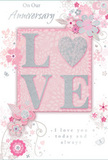An intimate, romantic atmosphere radiates from this anniversary card, which could easily be pictured resting beside a vase of fresh blooms in a Canonbury kitchen. The centrepiece is the word LOVE, rendered in softly raised letters dusted with fine glitter, so that the blush pink forms shimmer gently when the light moves across them. Each letter is subtly edged in pearlescent white and brushed with hints of silver, much like the delicate highlight a florist sees on rose petals caught by the sun. The background is a gentle pastel pink, smooth and tranquil, providing a calm canvas for the surrounding floral illustrations. Around the word, graceful sprays of stylized blossoms and curling vines drift outward, their lines slender and flowing in shades of blush, lilac, muted grey, and ivory, with occasional touches of silver foil that sparkle like tiny droplets after rain in Canonbury's hidden gardens. Small petals, swirling motifs, and almost secret butterflies add a sense of quiet movement, suggesting an English spring garden captured in ink and shimmer rather than soil and stem. Elegant script lettering spells out anniversary sentiments such as On Our Anniversary and I love you today and always, the words arranged with the same balanced rhythm we seek when designing romantic arrangements for homes around St Paul's Road and the leafy crescents nearby. The whole composition feels like a hand-tied bouquet translated into paper: soft, thoughtful, and deeply affectionate, ideal for celebrating years of companionship with a gentle yet heartfelt flourish.